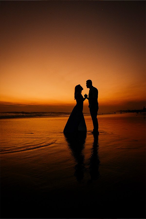 Couple silhouette holding hands on the beach at sunset