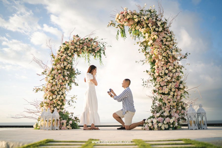Handre proposing to Selvi under a flower arch by the ocean