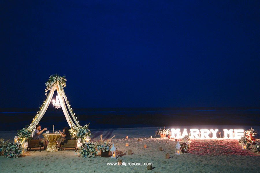 Beach dinner under a floral tent at night in Bali